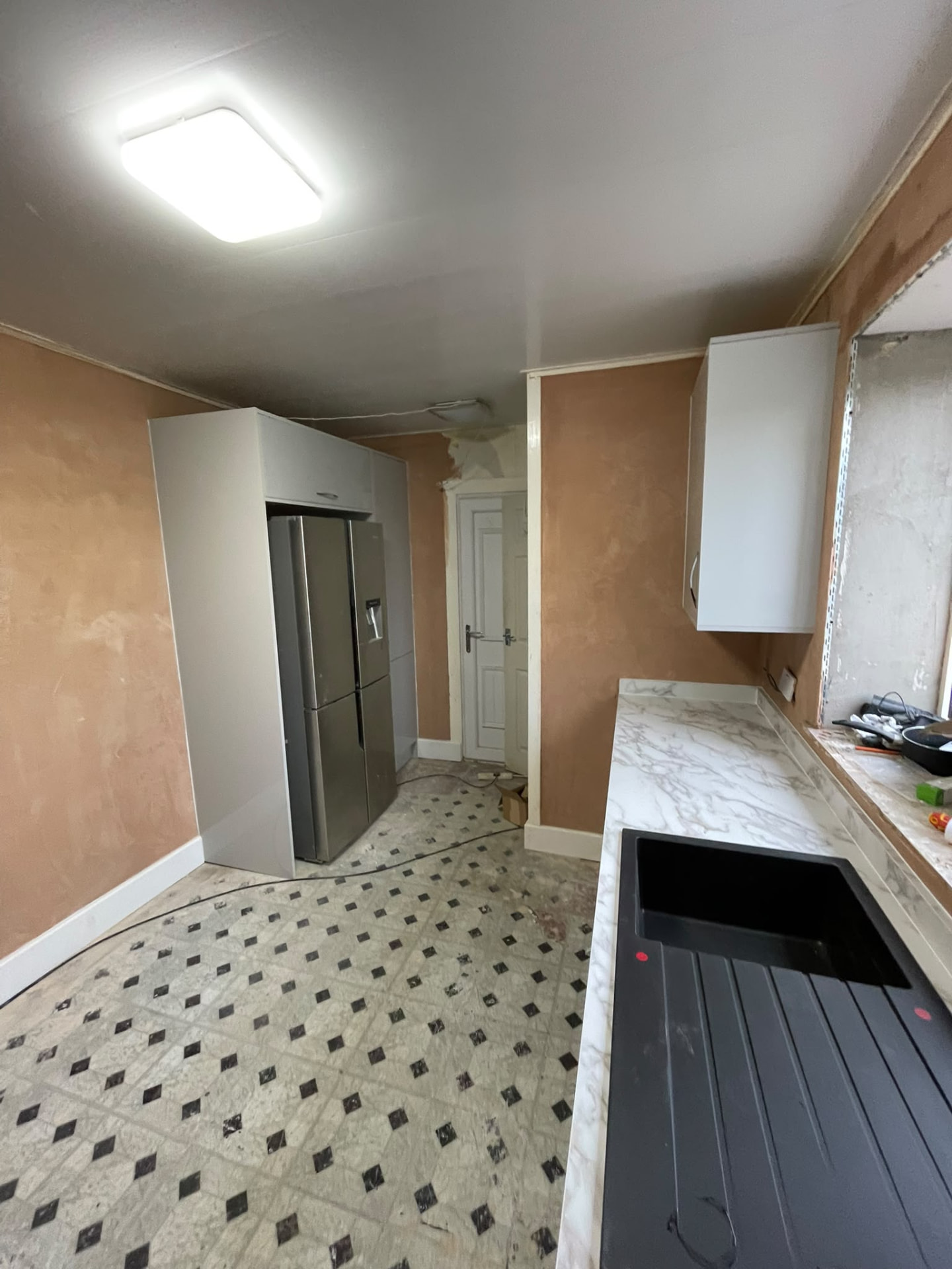 Tall white gloss appliance housing in a kitchen being fitted