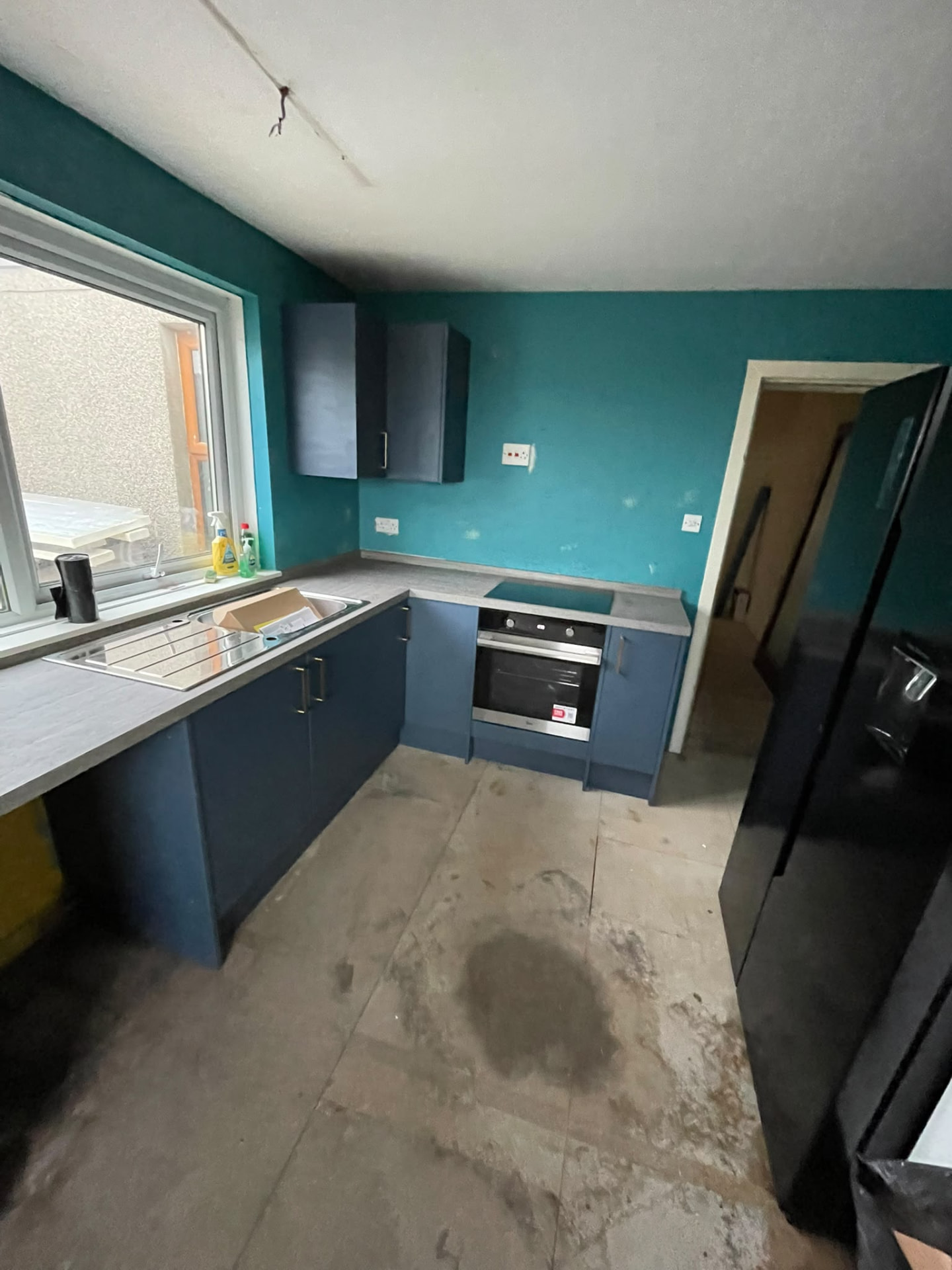 Dark blue kitchen units with grey wood-effect worktops fitted