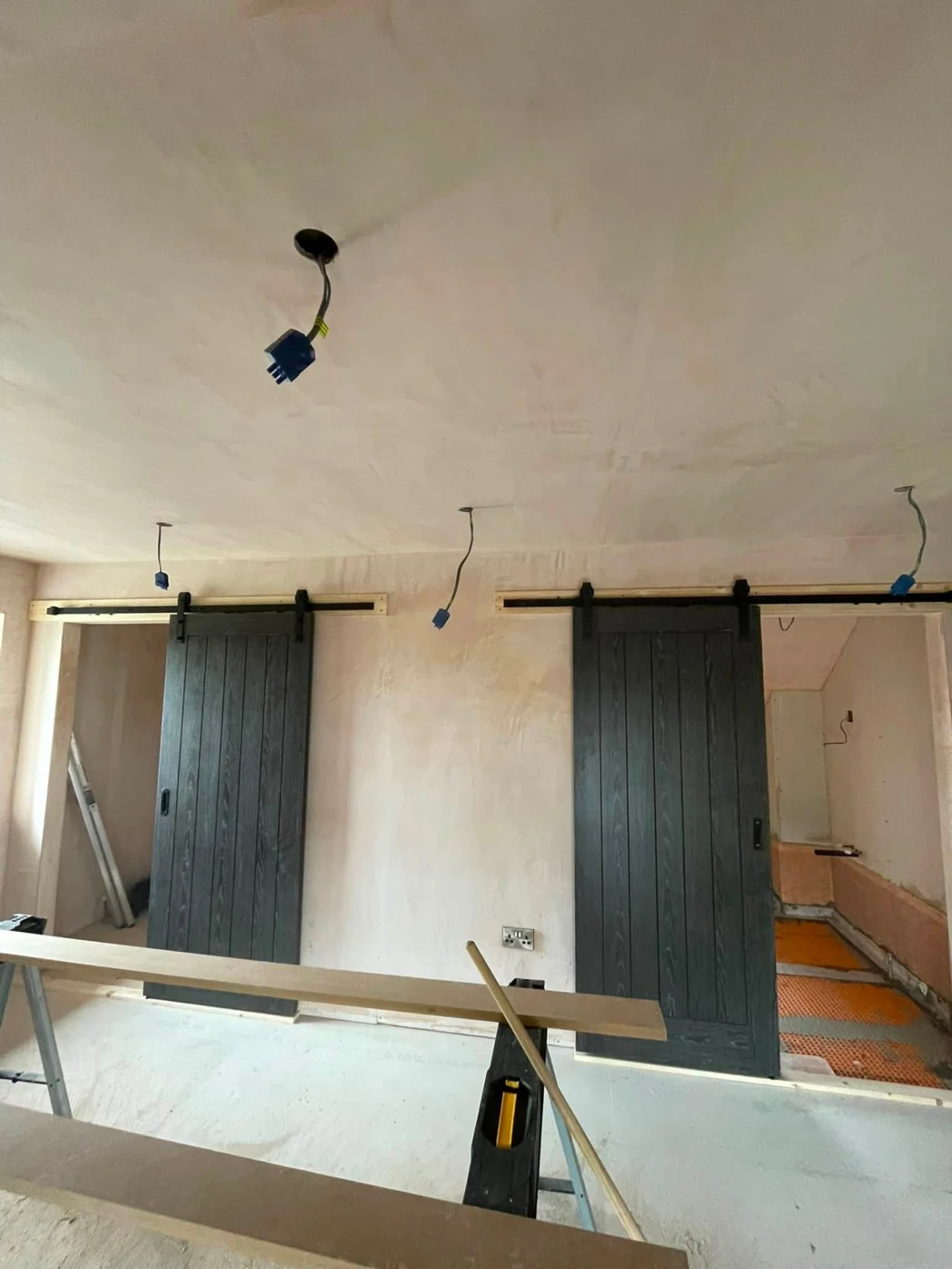 Dark timber barn-style sliding doors on exposed tracks during renovation